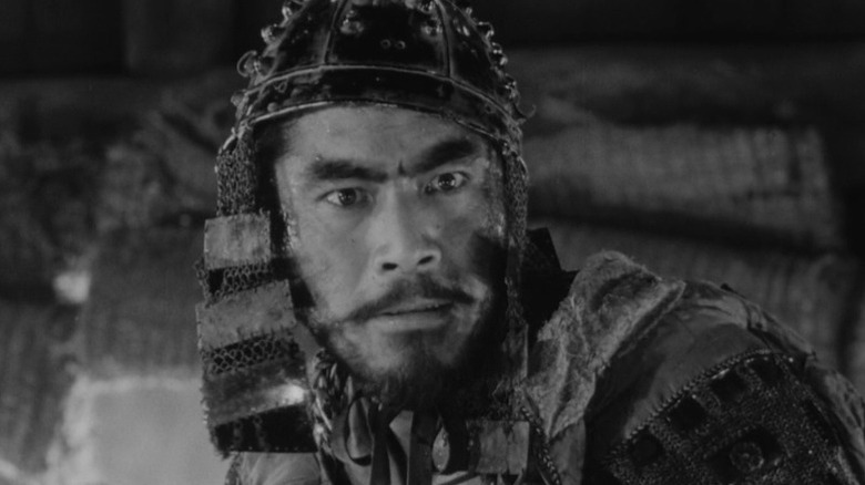 Toshiro Mifune as Kikuchiyo knitting his brows in full samurai armor in Seven Samurai