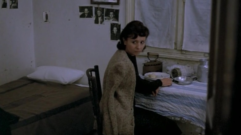 Eeva Kotatmanidou as Electra sitting at a table in a small bedroom in The Travelling Players