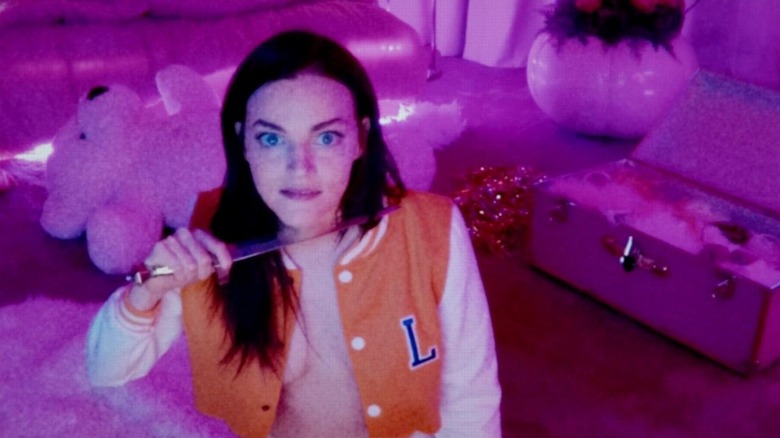 Alice (Madeline Brewer) puts a knife to her throat in a cam show in Cam