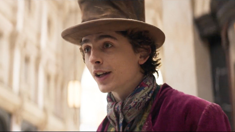 Willy Wonka (Timothée Chalamet) speaks in the street excitedly in Wonka