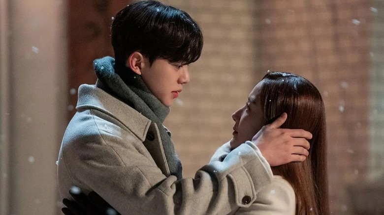 Lee Shi-woo (Song Kang) caresses the face of Jin Ha-kyung (Park Min-young) in the snow in Forecasting Love and Weather