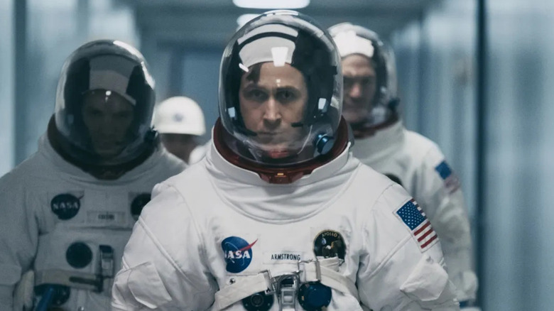 Ryan Gosling as Neil Armstrong, walking down the hallway in a NASA space suit in First Man