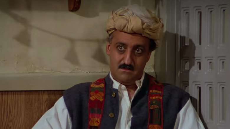 Brian George as Babu Bhatt sits in a corner in Seinfeld