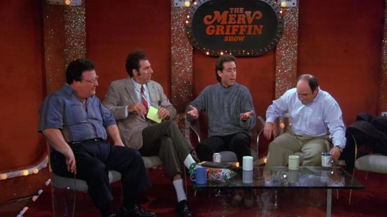 Newman (Wayne Knight), Kramer (Michael Richards), Jerry (Jerry Seinfeld), and George (Jason Alexander) sit on The Merv Griffin Show set in Seinfeld