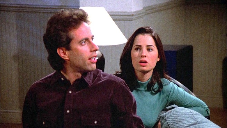 Jerry (Jerry Seinfeld) and Sharon (Paula Marshall) sit on a couch in Seinfeld