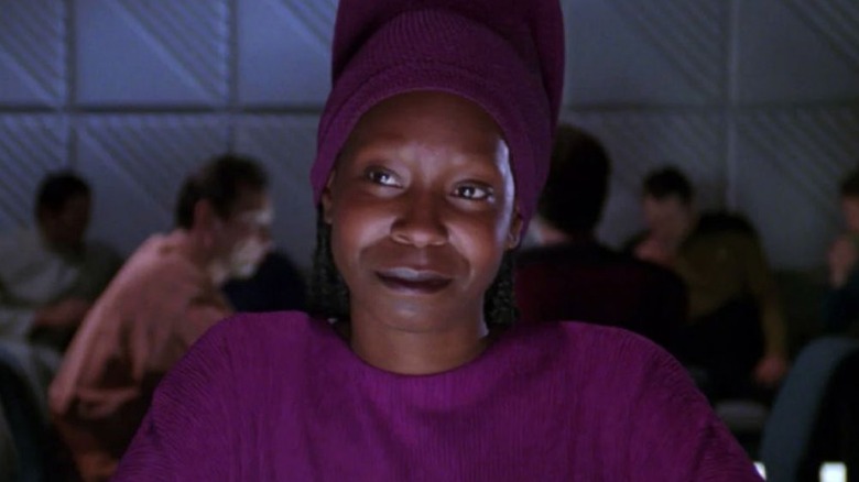 Guinan (Whoopi Goldberg) sits smiling at her bar in Star Trek: The Next Generation