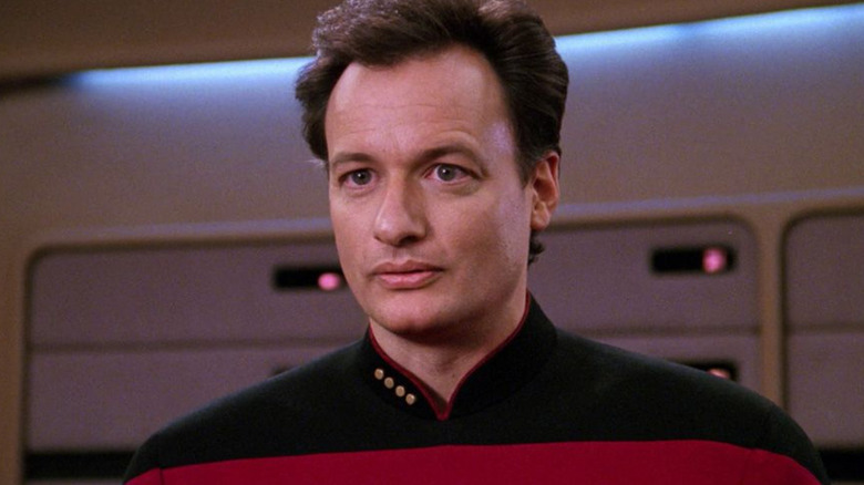 Q (John De Lancie) stands in a Starfleet uniform in Star Trek: The Next Generation