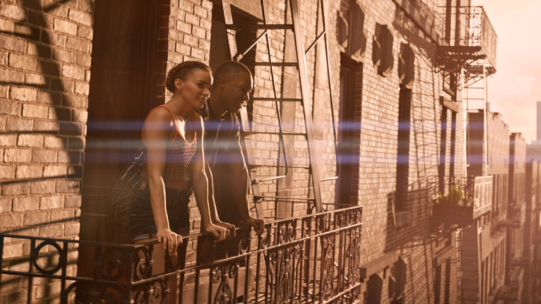Leslie Grace and Corey Hawkins as Nina and Benny on a balcony in In The Heights