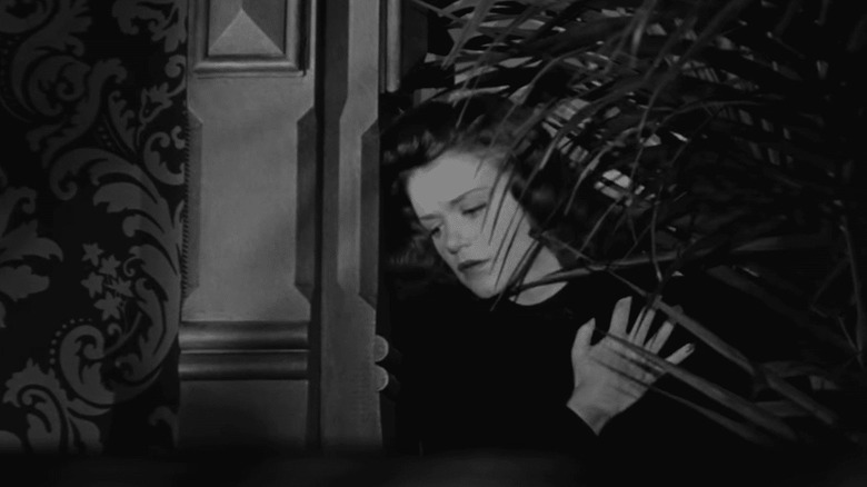 woman hides behind bush in Cat People