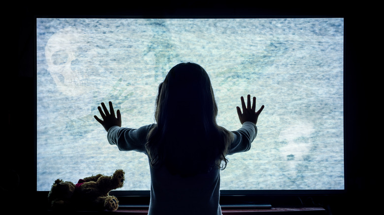 young girl in front of spooky tv