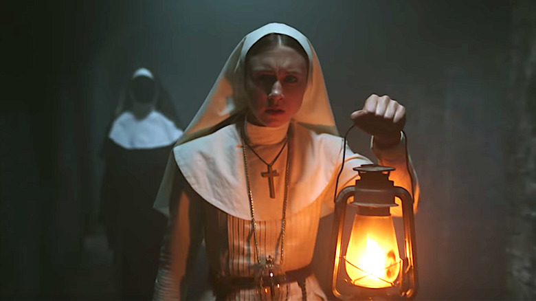 young nun in habit holds lamp