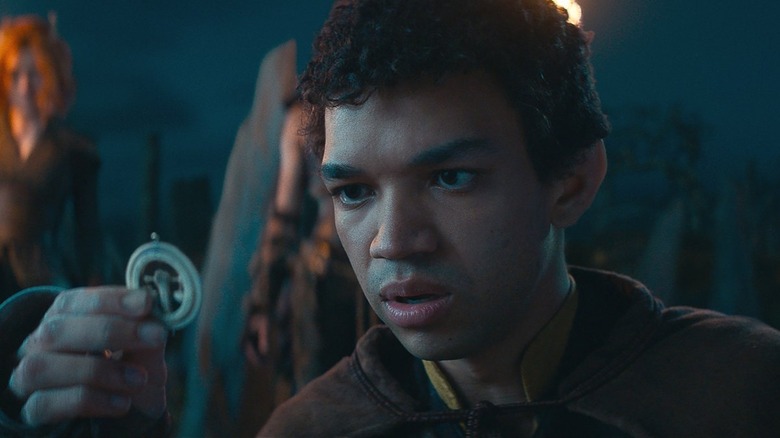 Justice Smith, as the hapless sorcerer, Simon, fiddles with an amulet