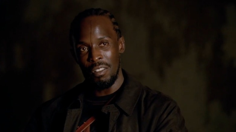 Michael K. Williams as Omar Little smiling bitterly in a dark room on The Wire