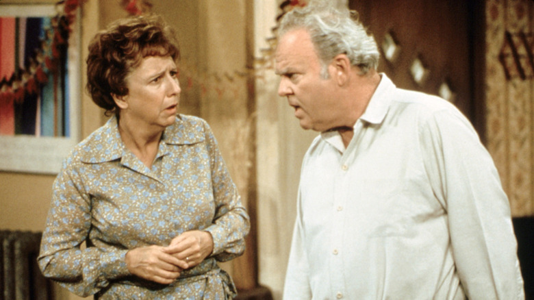 Archie Bunker (Carroll O'Connor) looks angrily at Edith Bunker (Jean Stapleton) in the living room in All in the Family