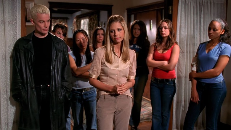 Sarah Michelle Gellar as Buffy stands next to James Marsters as Spike in front of the gang in Buffy the Vampire Slayer.