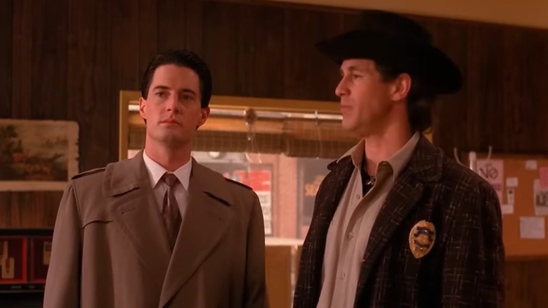 Kyle MacLachlan as Special Agent Dale Cooper stands next to sheriff in Twin Peaks.