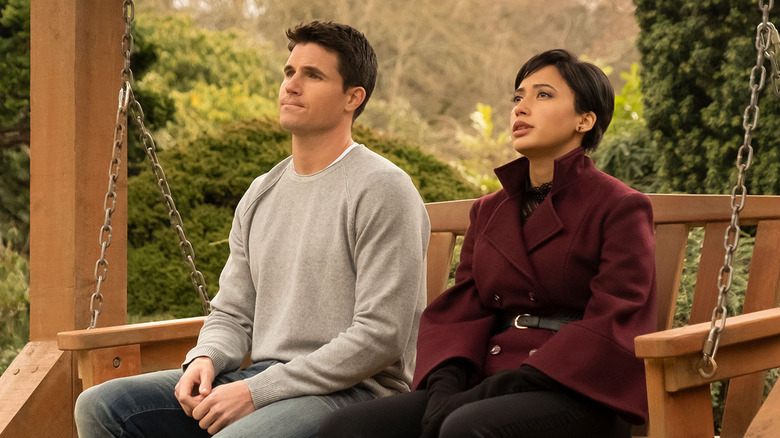 Robbie Amell as Nathan sitting on a bench with Andy Allo as Nora in Upload