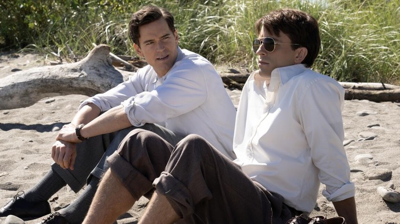 Jonathan Bailey and Matt Bomer as Hawkins and Tim, sitting together on the beach in Fellow Travelers