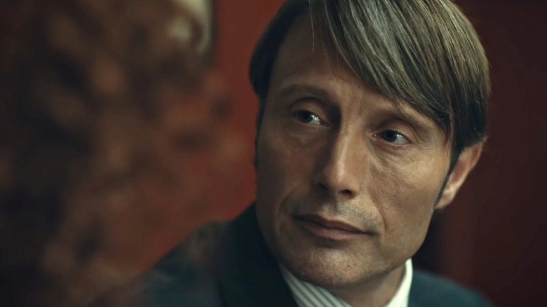 Mads Mikkelsen as Hannibal Lecter looks at a woman in Hannibal.