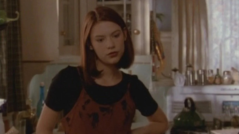 Claire Danes as Angela Chase stands in a kitchen in My So-Called Life.