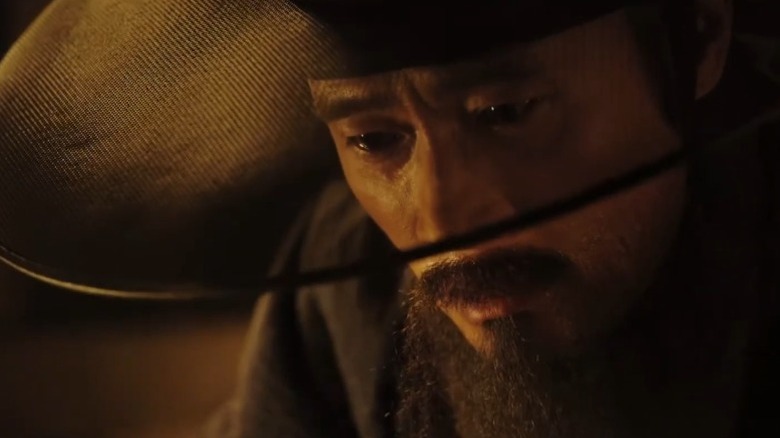 Lee Byung-hun as Choi Myung-kil wearing a hat with his head bowed in The Fortress