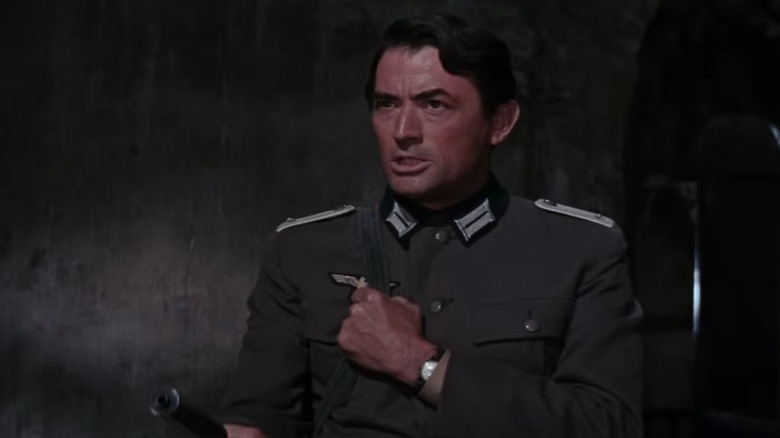Gregory Peck as Captain Keith Mallory holding a gun with his right hand and making a fist with his left in The Guns of Navarone