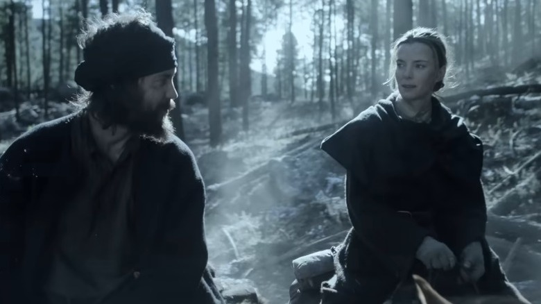 Taylor Kitsch as Isaac Reed and Betty Gilpin as Sara Holloway riding horses through a cold forest on American Primeval