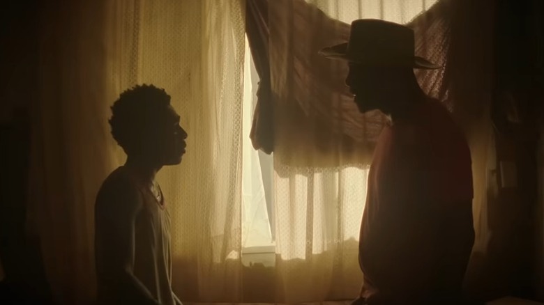 Caleb McLaughlin as Cole and Idris Elba as Harp standing face to face next to a window covered by curtains in Concrete Cowboy