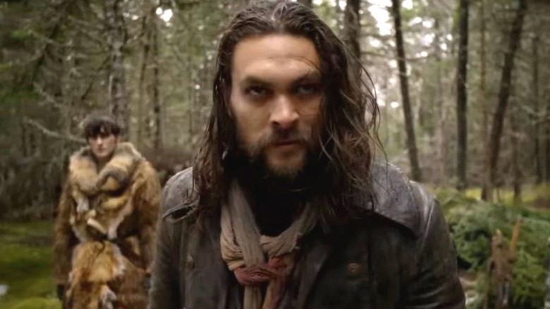 Jason Momoa as Declan Harp walking through a forest while Landon Liboiron as Michael Smyth walks behind him on Frontier