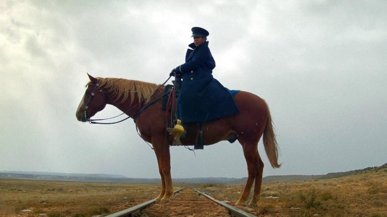 Regina King as Trudy Smith riding a horse standing on train tracks in The Harder They Fall