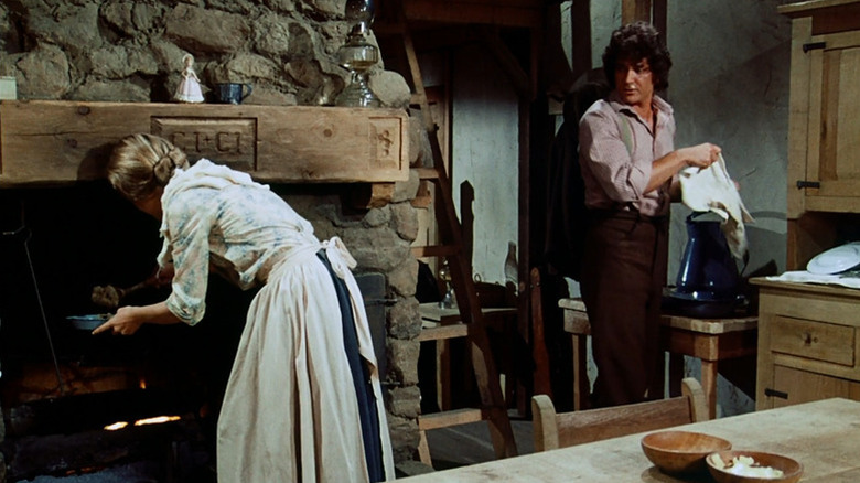 Charles Ingalls (Michael Landon) watches Caroline Ingalls (Karen Grassle) prepare dinner in Little House on the Prairie