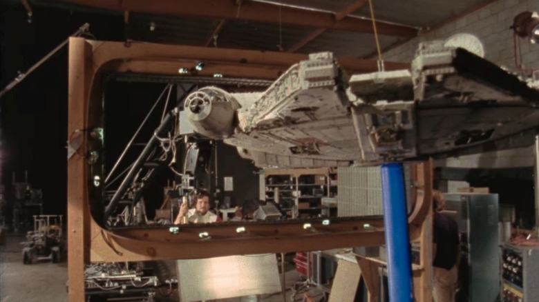 The Millennium Falcon hangs in front of a wooden frame with a crew member behind it in Light & Magic