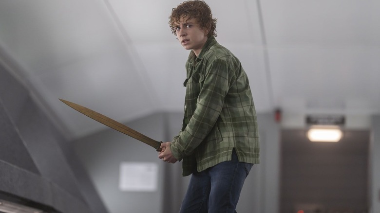 Walker Scobell as Percy Jackson stands while holding his sword in Percy Jackson and the Olympians