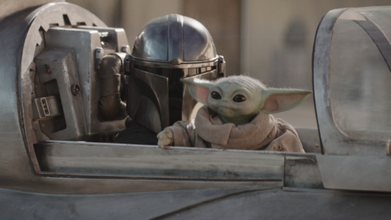 Pedro Pascal as Din Djarin sits next to Grogu in a spaceship in The Mandalorian