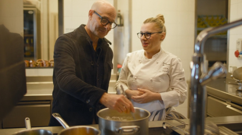 Stanley Tucci and chef Iside De Cesare stand over a stove while making pasta in Tucci in Italy