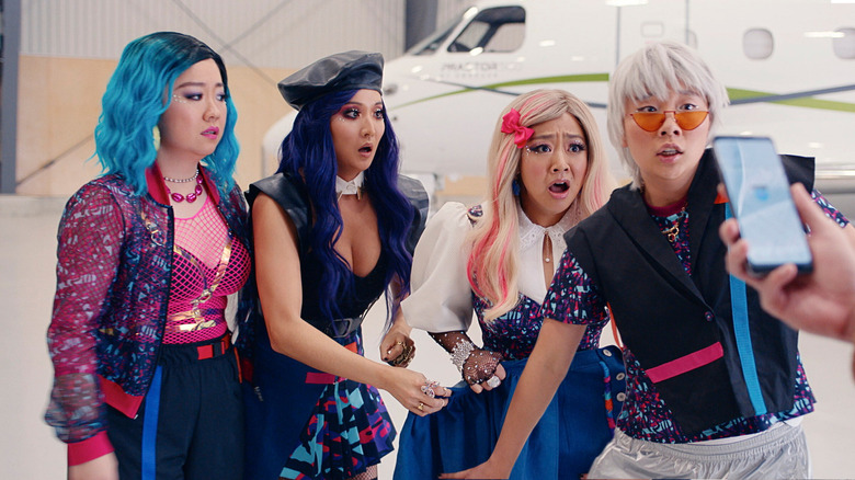 Sherry Cola as Lolo, Ashley Park as Audrey, Stephanie Hsu as Kat, and Sabrina Wu as Vanessa looking terrified while dressed as a K-pop girl group in an airport in Joy Ride