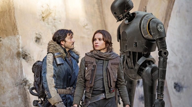 Jyn Erso standing in front of Cassian Andor and K-2SO