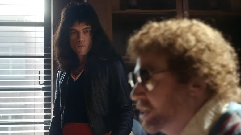 Freddie Mercury (Rami Malek) talking to a man in glasses in Bohemian Rhapsody