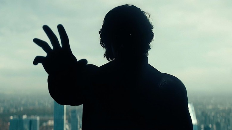 Lewis Pullman as Sentry floating in the sky and silhouetted with two glowing eyes and lifting his hand in Thunderbolts*