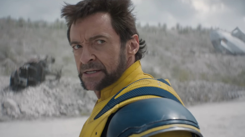 Hugh Jackman as Wolverine wearing his yellow suit and brandishing his claws under a cloudy sky in Deadpool & Wolverine