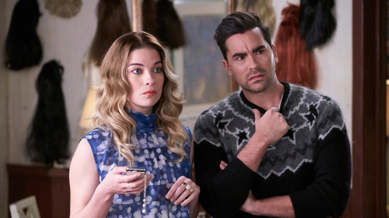 Alexis and David look on at something offscreen, both perplexed
