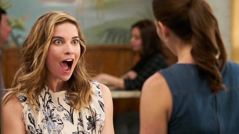 Alexis looks at a woman with a wide-mouthed smile
