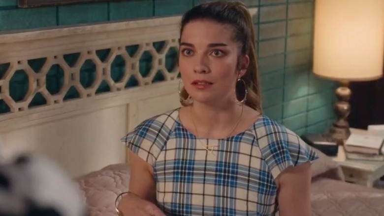 Alexis sits on her bed, looking concerned