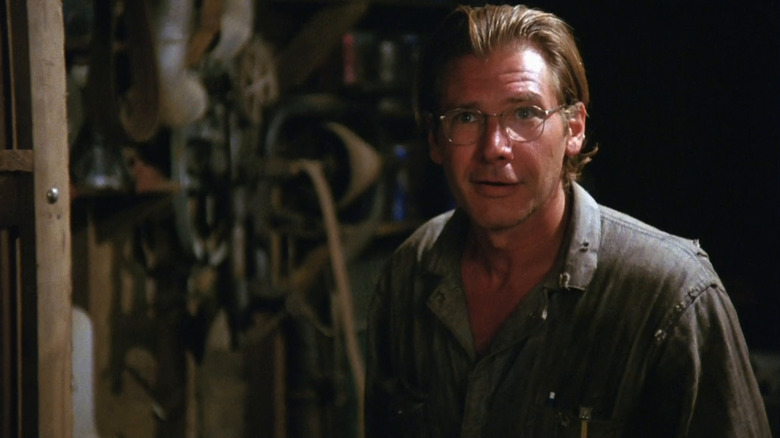Allie Fox (Harrison Ford) stands smirking outside in The Mosquito Coast