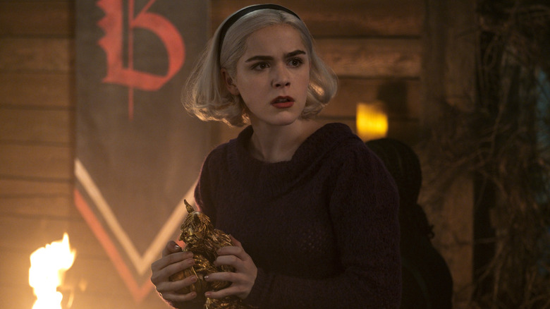 Kiernan Shipka's Sabrina Spellman holding a golden statue in her hands in Chilling Adventures of Sabrina