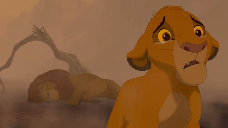 Simba sad with a dead Mufasa in the background in The Lion King