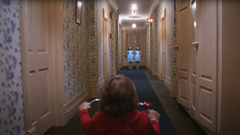 Two ghostly girls at the end of a hallway in Stanley Kubrick's "The Shining"
