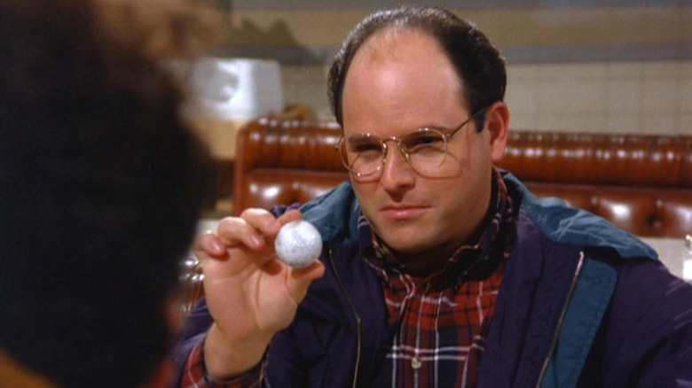 Jason Alexander as George Costanza holding a golf ball in Seinfeld