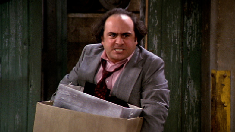 Danny DeVito as Louie De Palma angrily carrying a box of things in Taxi