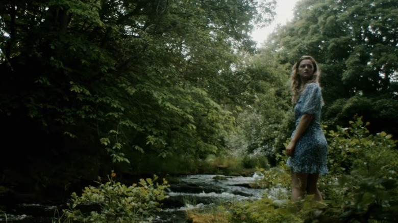 Lizzy Willis as Alice standing next to a stream in Alice in Terrorland